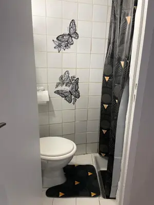 a bathroom with a toilet and a shower curtain with butterflies at iNICE in Nice