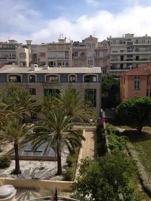 a building with palm trees in front of a city at Superbe Studio in Nice at 450m from the sea with Clim in Nice