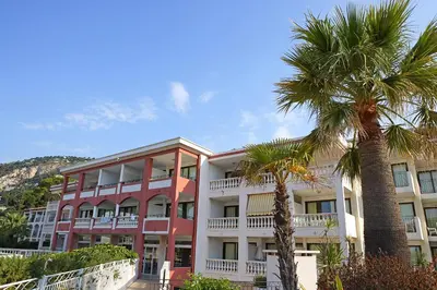 a building with palm trees in front of it at Résidence Pierre & Vacances l'Ange Gardien in Villefranche-sur-Mer