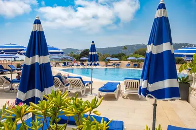 a pool at a resort with blue and white umbrellas at Résidence Pierre & Vacances l'Ange Gardien in Villefranche-sur-Mer