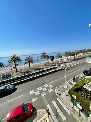 a road with cars parked on the side of the beach at Promenade des Anglais panoramic sea view in Nice