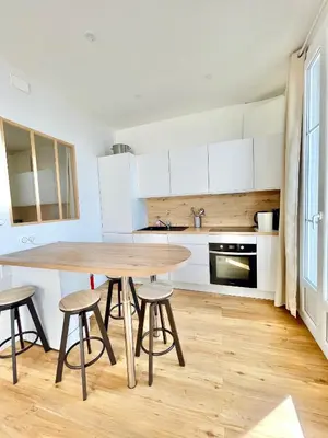 a kitchen with a wooden table and stools at Promenade des Anglais panoramic sea view in Nice