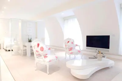 a white bathroom with a tub and a living room at Boscolo Nice Hotel & Spa in Nice
