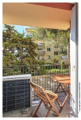 a patio with a table and a bench on a balcony at Parc Anahit in Nice
