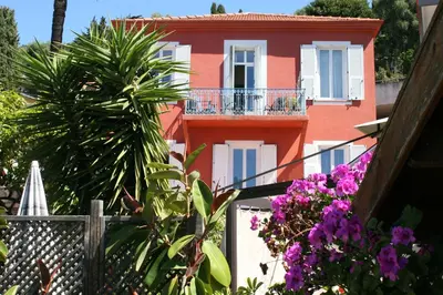 a pink house with flowers in front of it at Hôtel La Villa Patricia - Charme et Tradition in Villefranche-sur-Mer