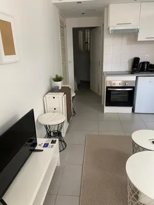 a kitchen with white appliances and tables and chairs at Au cœur de St Jean Cap Ferrat in Saint-Jean-Cap-Ferrat