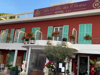 a red building with green shutters and a hotel at Hôtel La Villa des Oliviers in Cagnes-sur-Mer