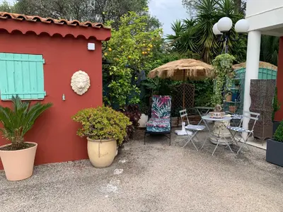 a patio with a table and chairs and a red wall at Hôtel La Villa des Oliviers in Cagnes-sur-Mer