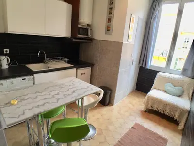 a kitchen with a sink and a table with green chairs at Niceaparts in Nice