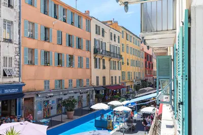 a city street with tables and umbrellas and buildings at Amazing 3 Bdrs and Garden Place du Pin Parking ! in Nice