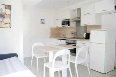 a white kitchen with a wooden table and white chairs at Sunny apartment in heart of Nice Old Town in Nice
