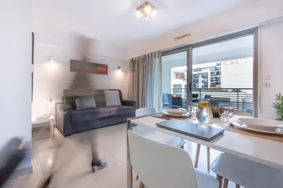 a living room with a table and chairs and a couch at Nemea Appart Hotel Le Lido Cagnes sur Mer in Cagnes-sur-Mer