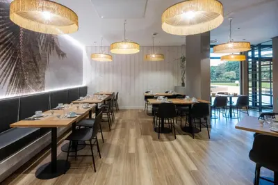 a dining room with tables and chairs and chandeliers at Nemea Appart Hotel Le Lido Cagnes sur Mer in Cagnes-sur-Mer