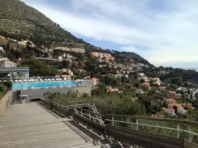 a boardwalk leading up to a building with a mountain at Appt 5 personnes vue mer piscine Costa Plana Cap d'Ail Monaco in Cap d'Ail