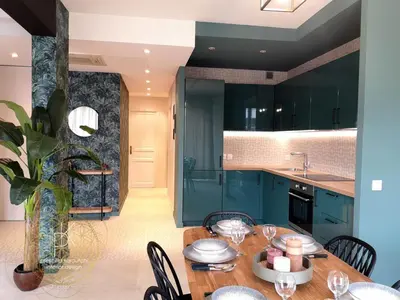 a kitchen with blue cabinets and a wooden table at Appartement Carré d'Or Vue sur Mer in Nice