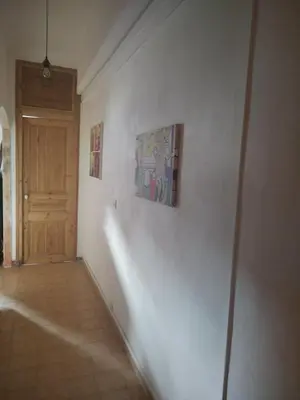 a hallway with a white wall with paintings and a door at Chez Brigitte Guesthouse in Nice