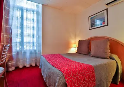 a bedroom with a bed with a red blanket at Hôtel restaurant Oasis in Nice