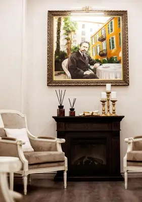 a painting of a man sitting in a chair next to a fireplace at Hôtel restaurant Oasis in Nice