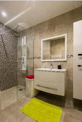 a bathroom with a sink and a shower with a yellow rug at La Lanterne Plage in Nice