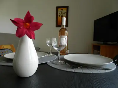 a table with a white vase with a flower in it at Les Pins . 2 p calme et terrasse in Nice