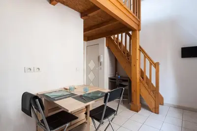 a dining room with a wooden table and a staircase at Aoustin in Nice