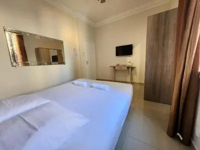 a bedroom with a white bed and a mirror at Promenade Appartements les Lions in Nice
