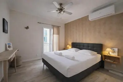 a bedroom with a large white bed with a ceiling fan at Promenade Appartements les Lions in Nice