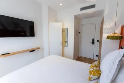 a white bedroom with a bed and a flat screen tv at Maison Durante in Nice