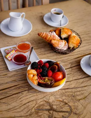 a table with a bowl of fruit and a plate of pastries at Hôtel Eze Hermitage in Èze