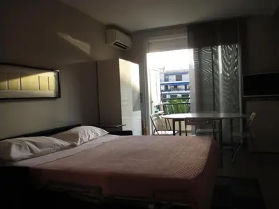 a bedroom with a bed and a table and a window at Appartement Cattleya - rue halevy in Nice