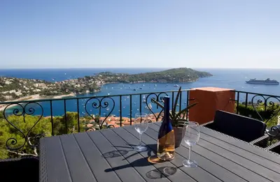a wooden table with two wine glasses on a balcony at Le Rooftop 180 in Villefranche-sur-Mer