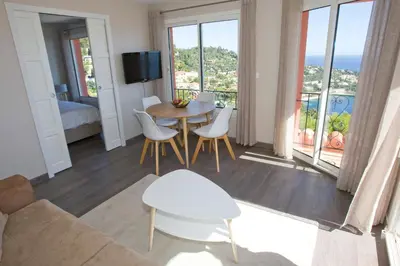a living room with a table and chairs and a balcony at Le Rooftop 180 in Villefranche-sur-Mer