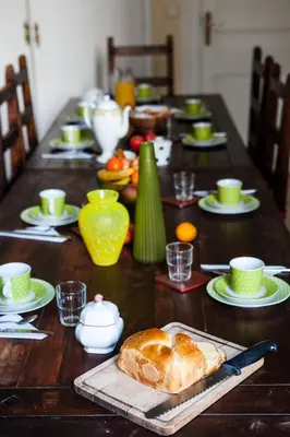 a wooden table with a long table with bread and cups at Nice Riviera Sweet Home Chambres d'hotes in Nice
