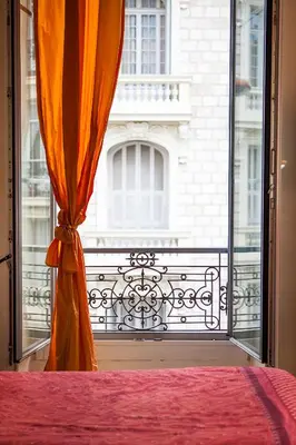 a bedroom with a window with an orange curtain at Nice Riviera Sweet Home Chambres d'hotes in Nice