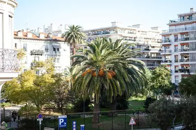 a palm tree in a city with buildings at Nice Riviera Sweet Home Chambres d'hotes in Nice