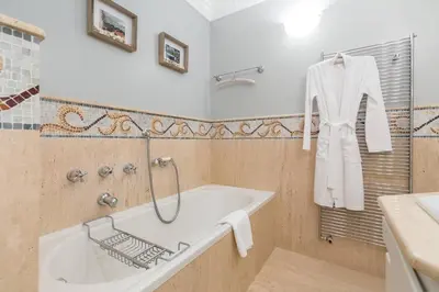 a bathroom with a tub and a white robe on a rack at Le Corot in Beaulieu-sur-Mer
