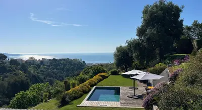 an outdoor swimming pool with an umbrella and the ocean at La Coulina in Nice