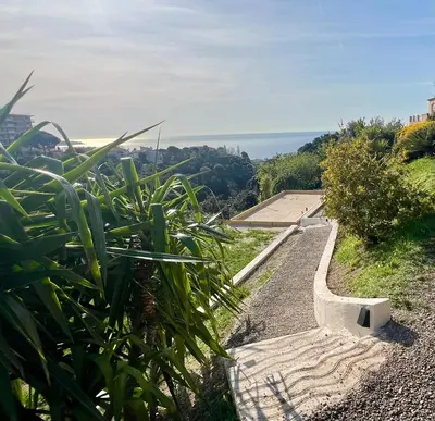 a path leading down a hill with a view of the ocean at La Coulina in Nice
