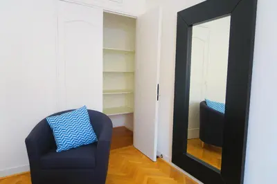 a mirror in a room with a blue chair and a blue pillow at Carré d’Or Appt 4 Pièces moderne et spacieux in Nice