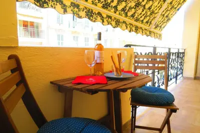a table with a glass of wine and two chairs at Carré d’Or Appt 4 Pièces moderne et spacieux in Nice