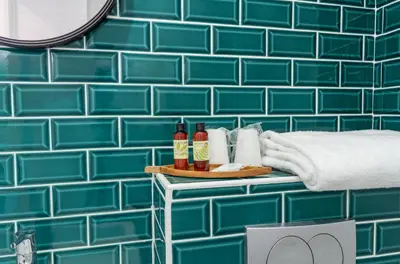 a blue tiled bathroom with a table with bottles and towels at Hotel Nap By HappyCulture in Nice