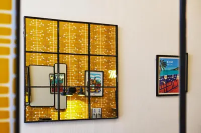 a mirror hanging on a wall with three pictures at Hotel Nap By HappyCulture in Nice