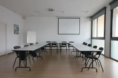 a conference room with tables and chairs and a white wall at Esatitude Hotel in Nice