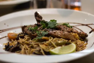 a white plate of food with noodles and meat at Esatitude Hotel in Nice