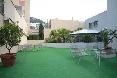 a courtyard with chairs and tables on a green floor at Esatitude Hotel in Nice