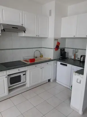 a kitchen with white cabinets and a sink at Appart bas Fabron in Nice