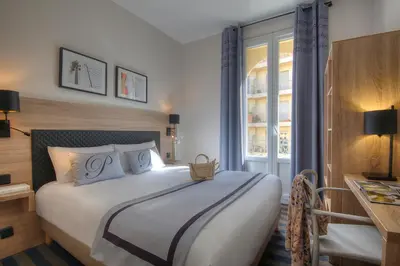 a bedroom with a large bed and a window at Hotel Paganini in Nice