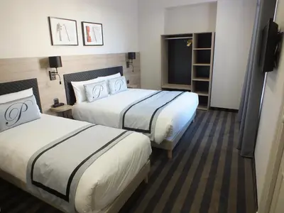 a hotel room with two beds and a television at Hotel Paganini in Nice