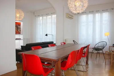 a dining room with a wooden table and red chairs at Le Maréchal in Nice