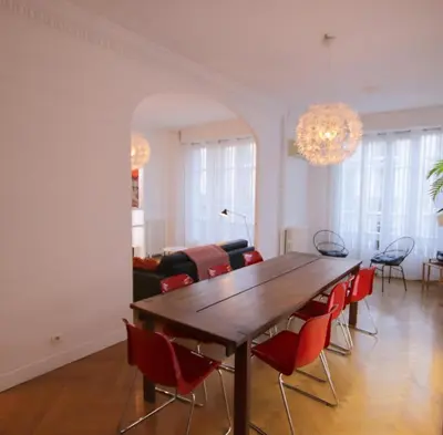 a living room with a wooden table and red chairs at Le Maréchal in Nice